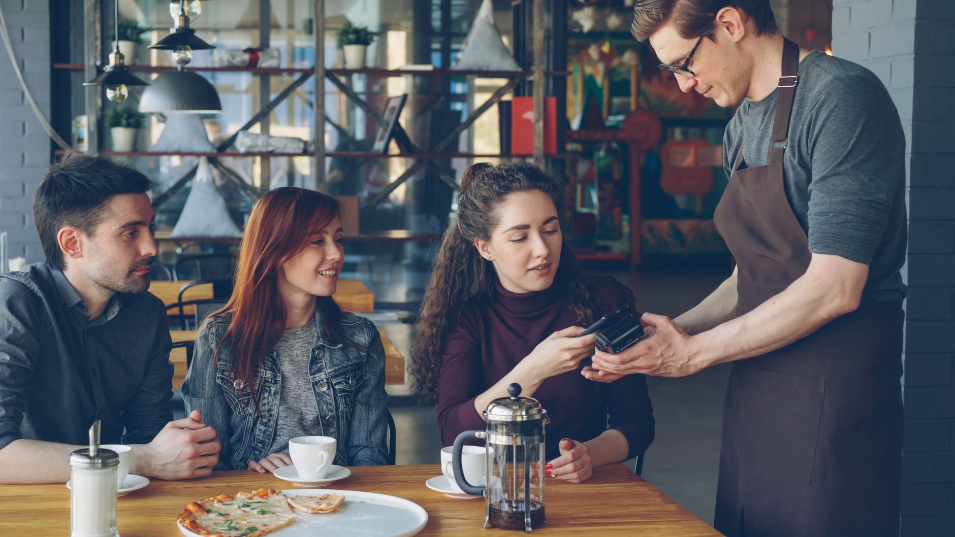 Group of friends at a café paying the bill with a card — Photo by Vitaly Gariev on Pexels