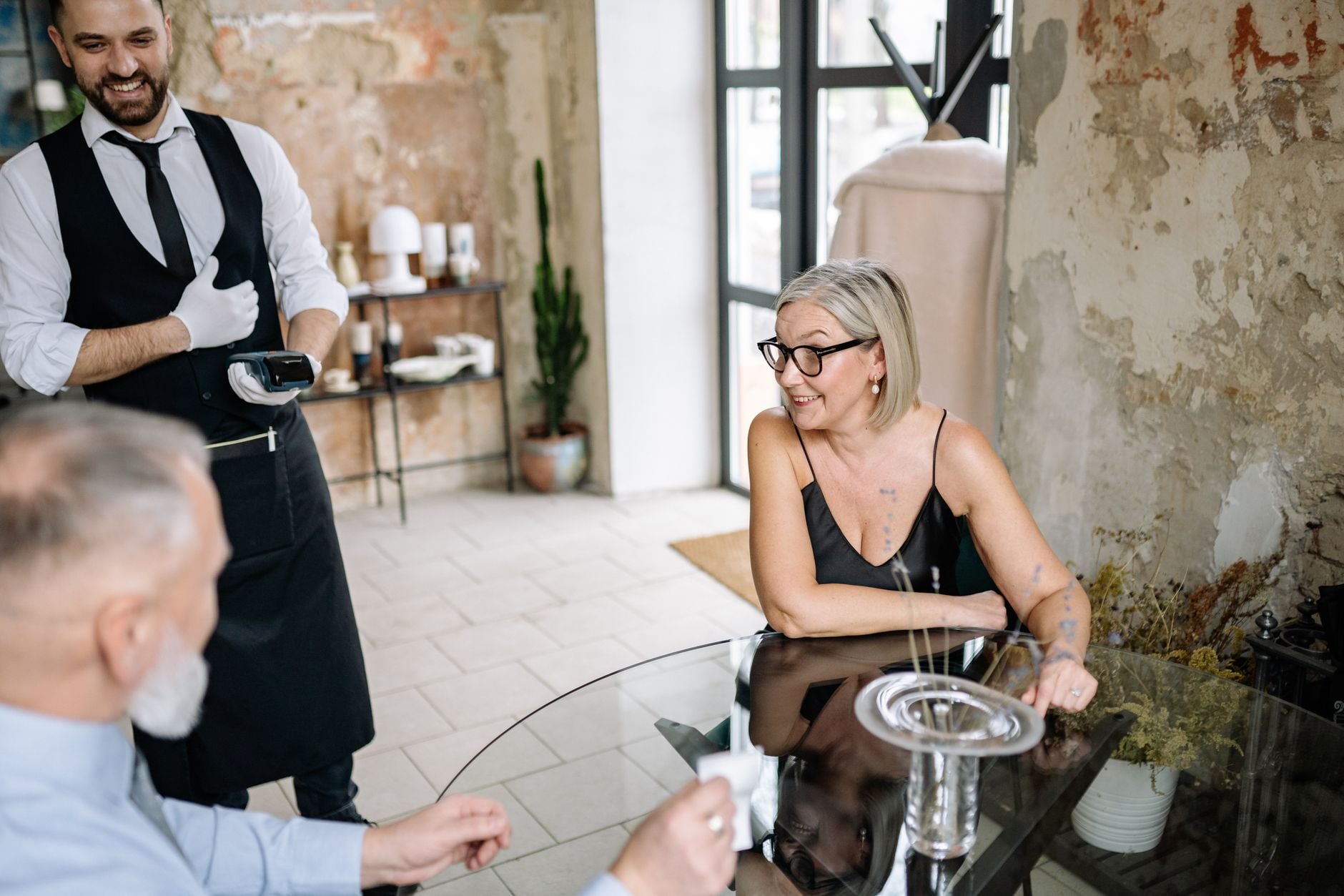 Waiter with a card reader serving customers at a restaurant table — Photo by Yan Krukau on Pexels