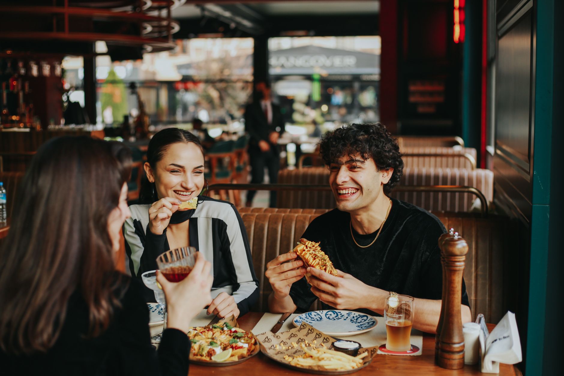 Group of friends laughing and eating at a restaurant, enjoying leisure time. Photo by Taha Samet Arslan on Pexels