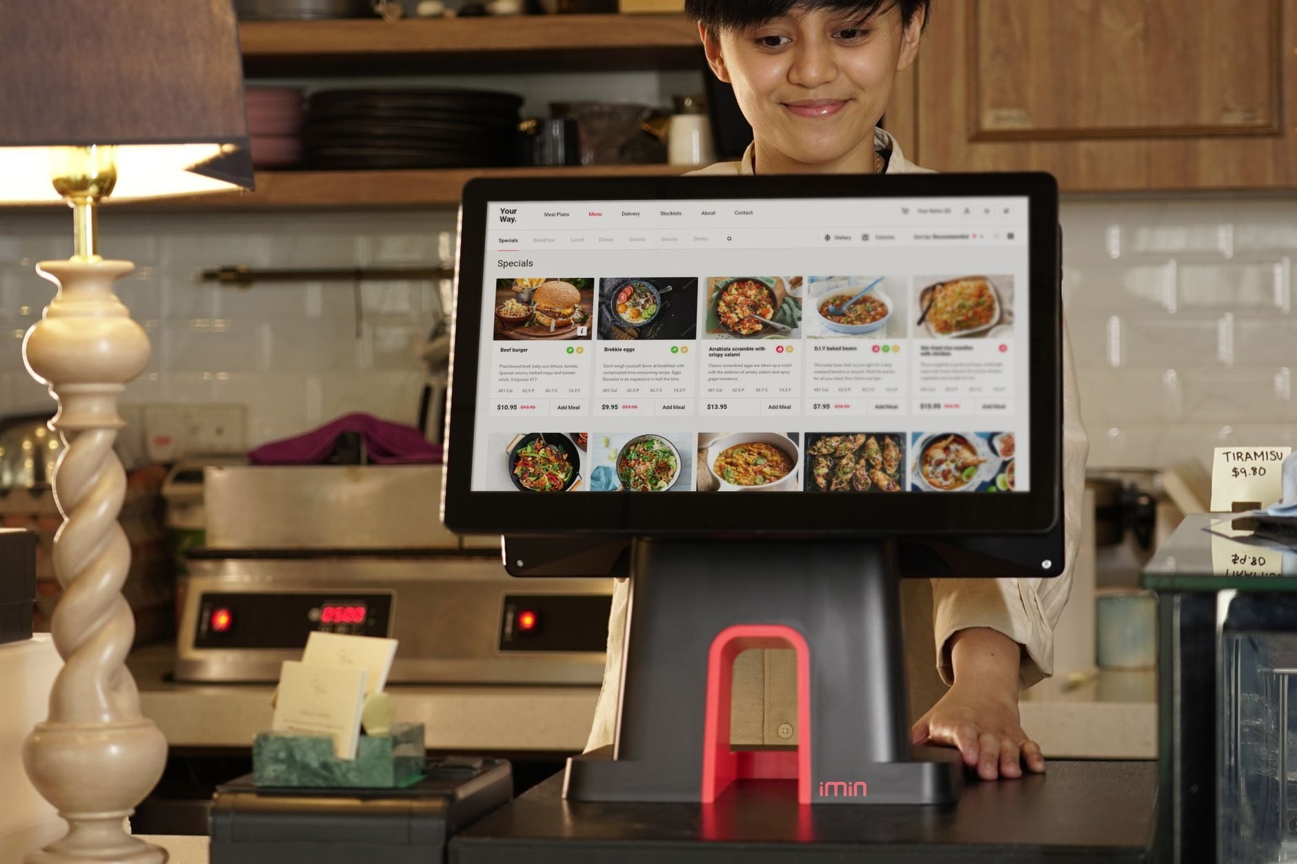A cashier uses a touchscreen system for taking orders in a restaurant setting. Photo by iMin Technology on Pexels