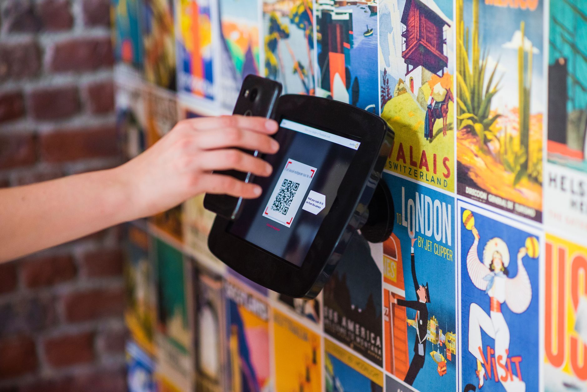 A hand scanning a QR code with a smartphone in a busy venue. Photo by Proxyclick Visitor Management System on Pexels