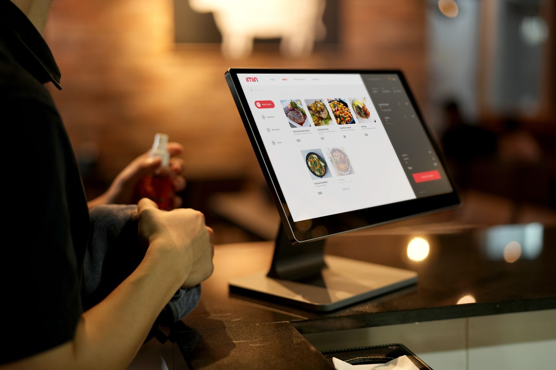 A person using a touchscreen ordering system in a modern restaurant setting. Photo by iMin Technology on Pexels