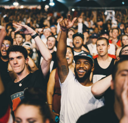 Various people in a crowd at a concert smiling and dancing