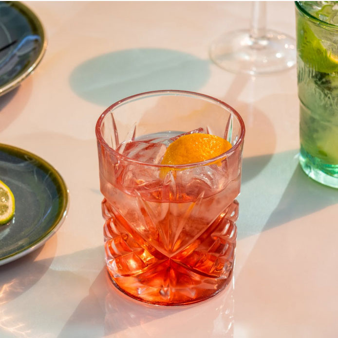 Centred Negroni in a crystal glass surrounded by other various cocktails